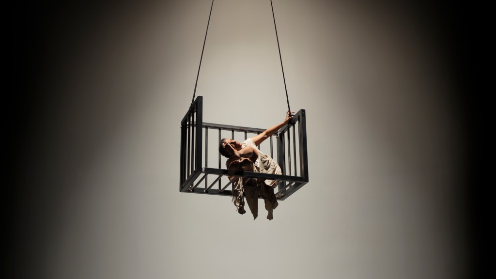 Dancer Laura Elaine Ellis leans gracefully off the side of a hanging metal cage for "Meet Us Quickly with Your Mercy"