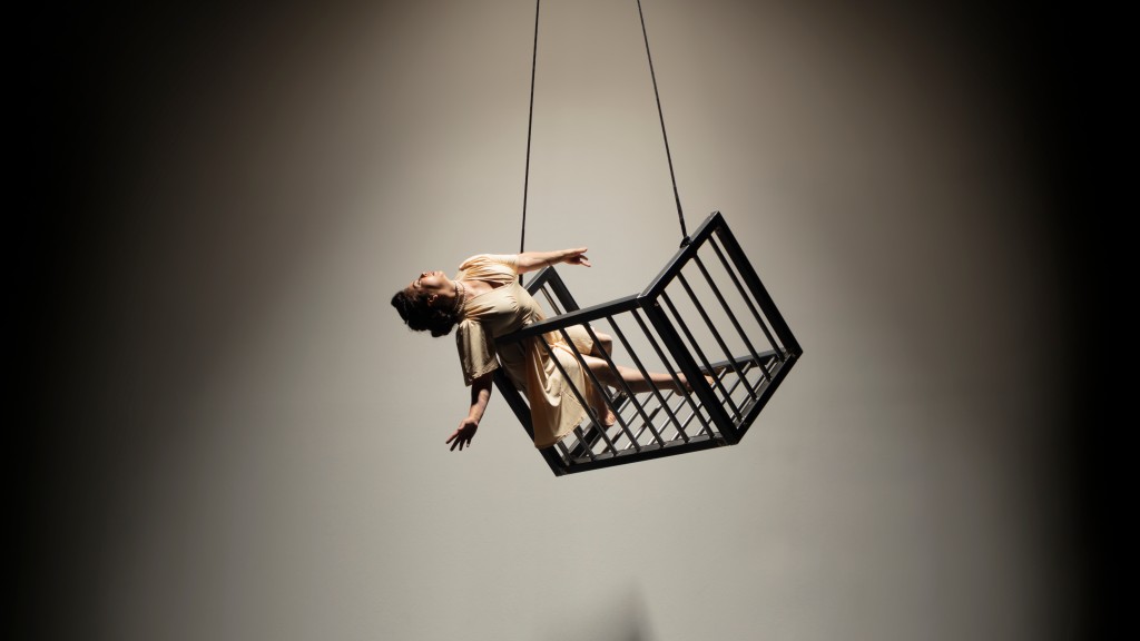 Dancer Bianca Cabrera leans gracefully off the side of a hanging metal cage for "Meet Us Quickly with Your Mercy"