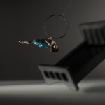 Megan Lowe arched in an aerial hoop, surrounded by floating beds.