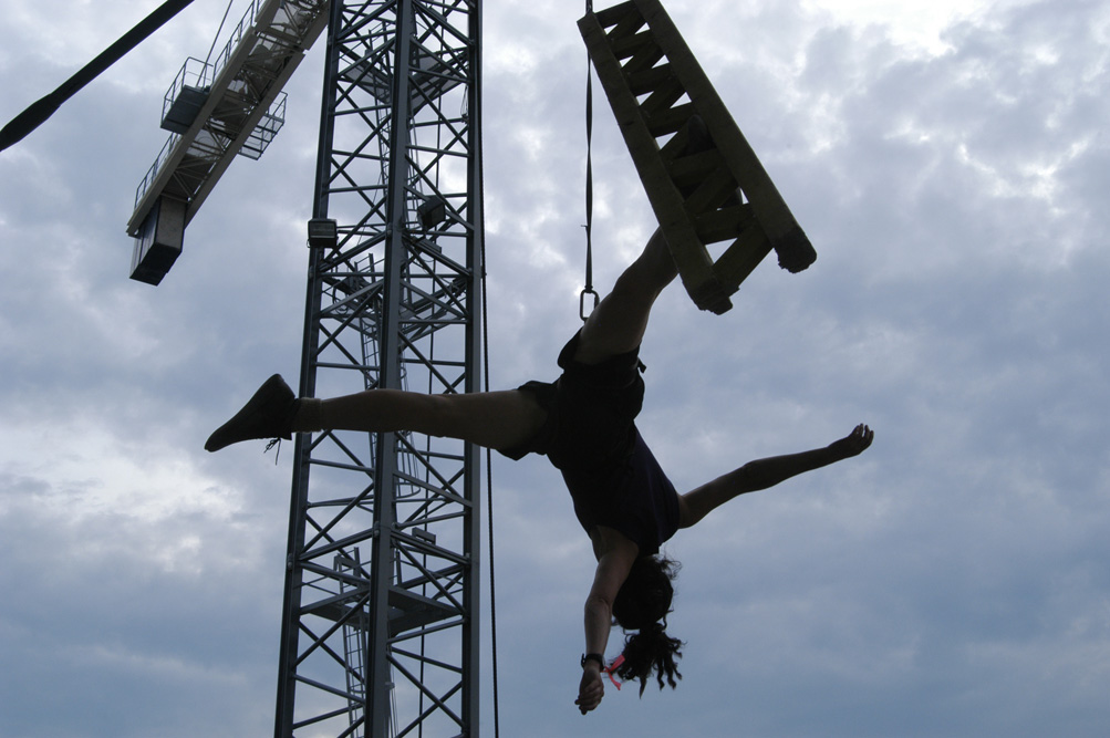 Jo Kreiter suspended via rope and harness from the side of a crane.