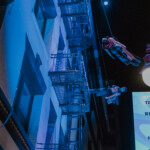 Megan Lowe and B Dean dancing on a fire escape suspended by rope and harness